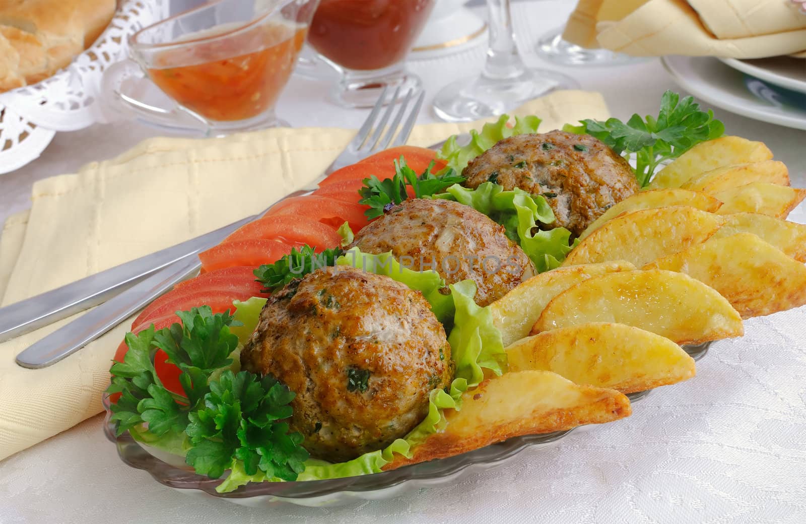 Meatballs with greens on salad leaves with potatoes and tomatoes
