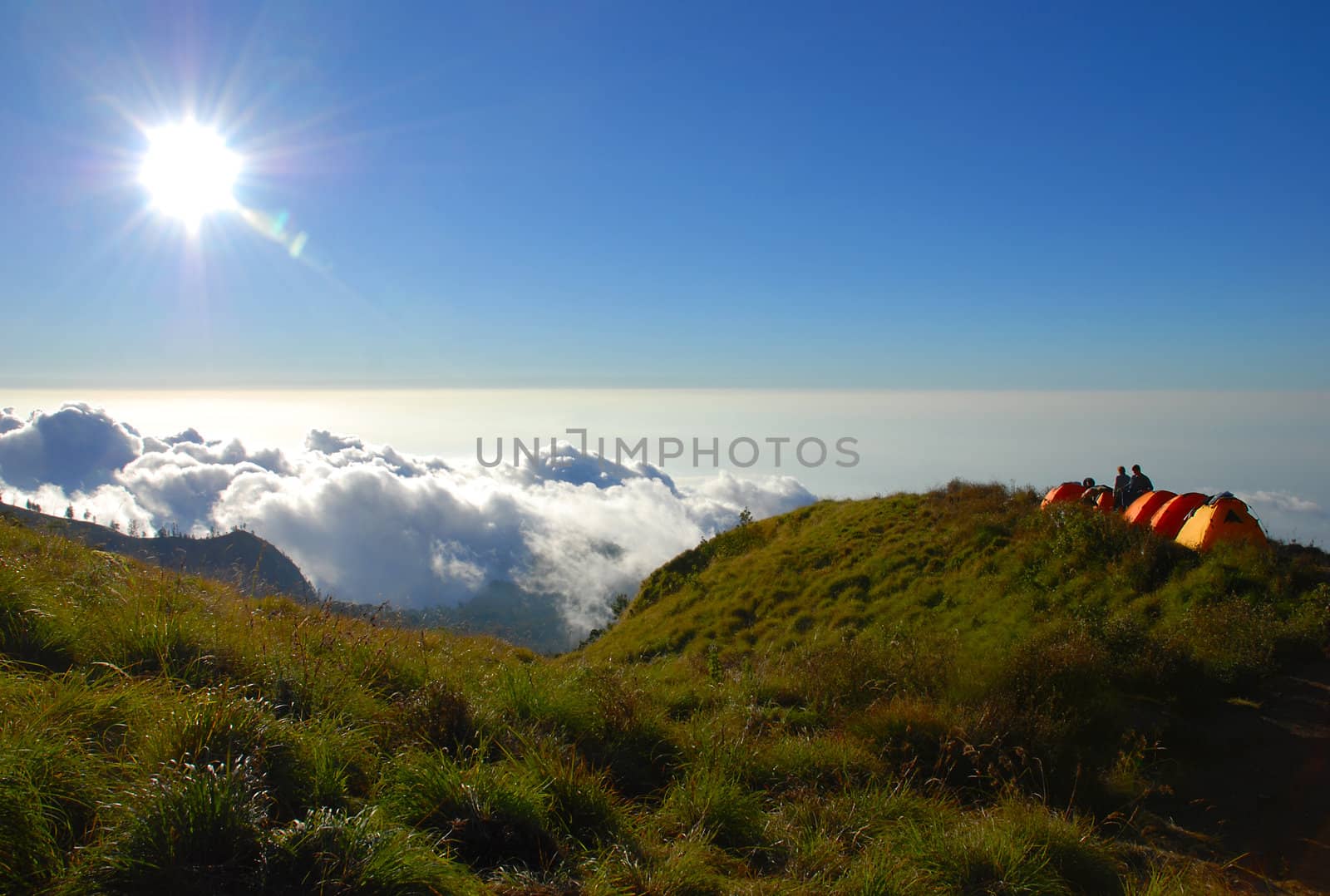 tents on the hillside above the clouds at sunset