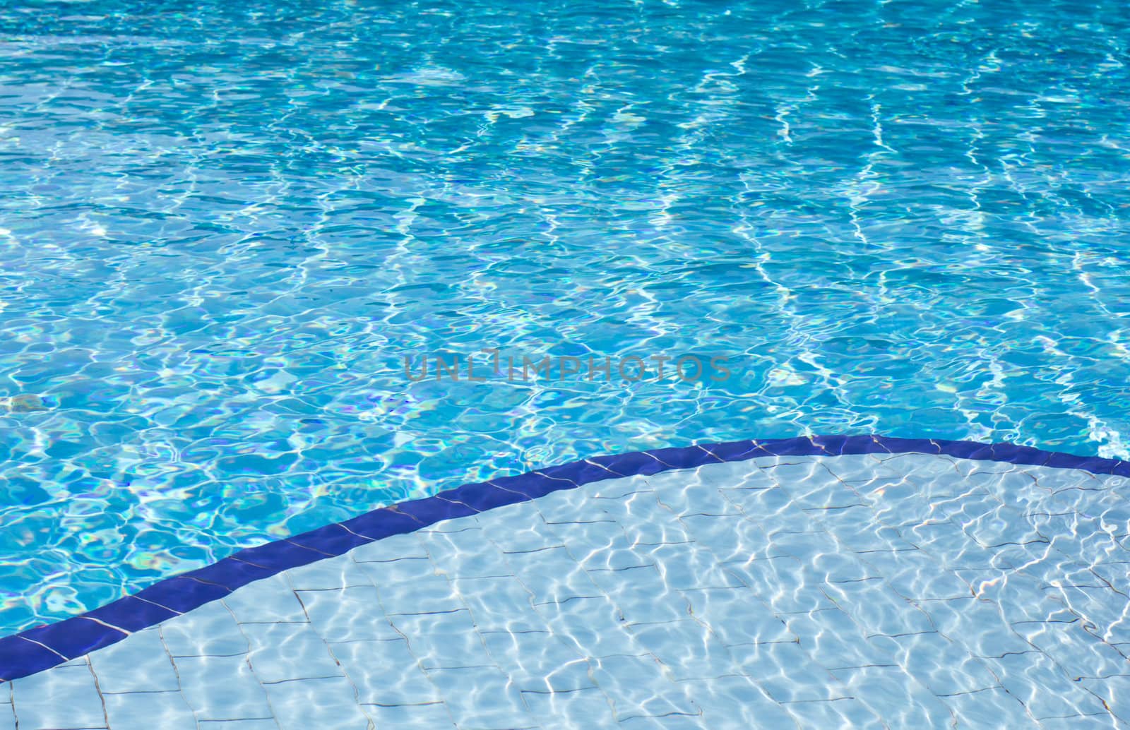 Background of clear blue water with sun reflections in an outdoor swimming pool with two different depths, a shallow and a deep depth.