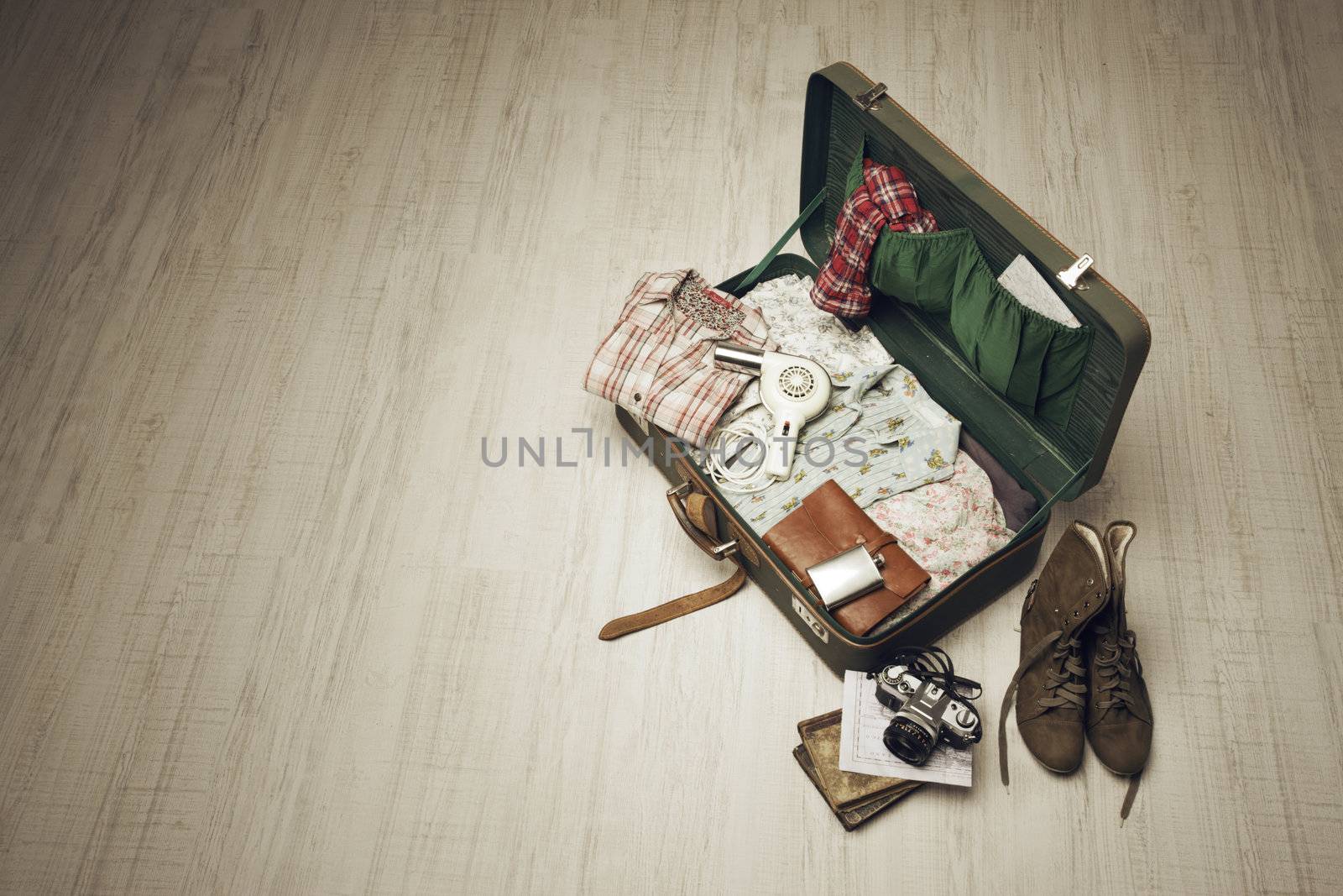 Vintage suitcase open on a wood floor in an empty room