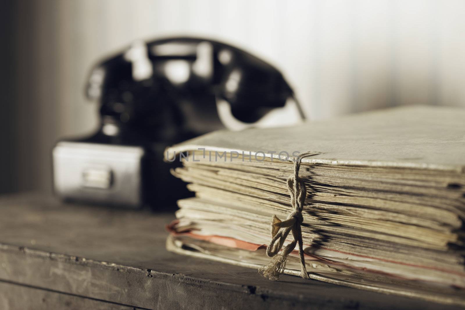 Old phone on a desk with documents by stokkete