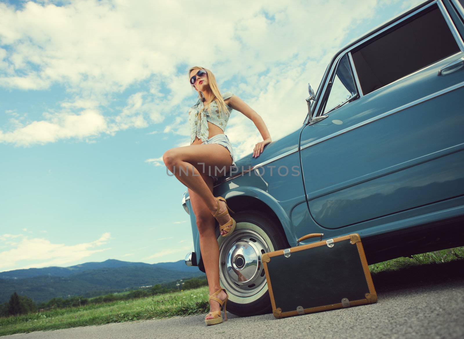 Fashion model with vintage cars, cloudy sky on background