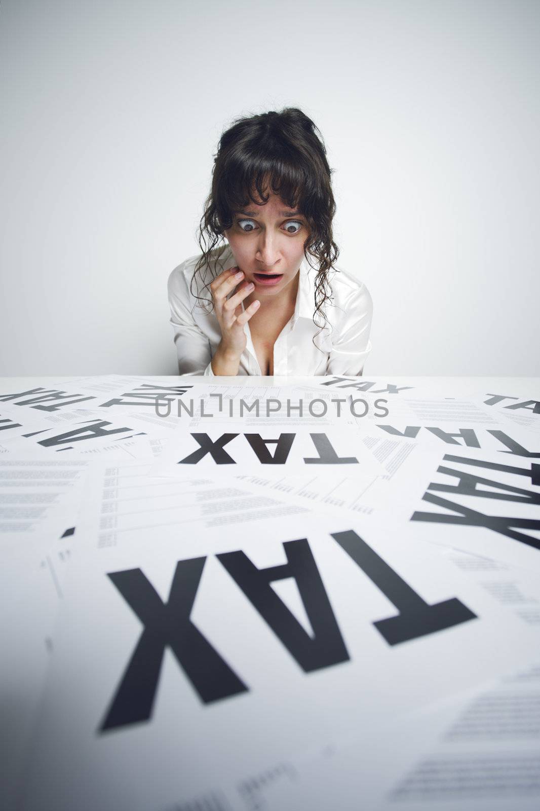 Astonished businesswoman looking at a bunch of worrying tax forms on her desk