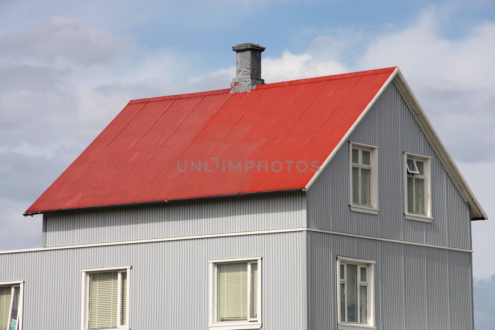 Small red roofed generic home in Iceland. Corrugated tin walls. Typical Nordic residential architecture.