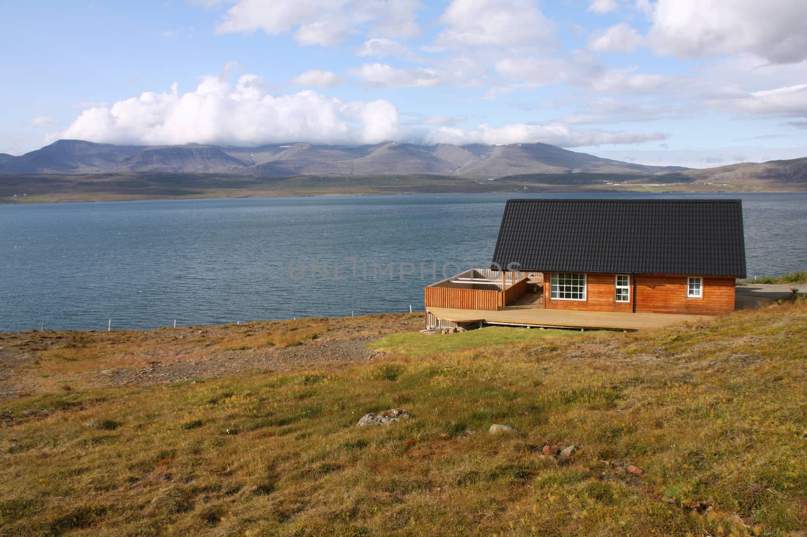 Small generic wooden lodge home next to Hvalfjordur fiord in Iceland. Typical Nordic residential architecture.