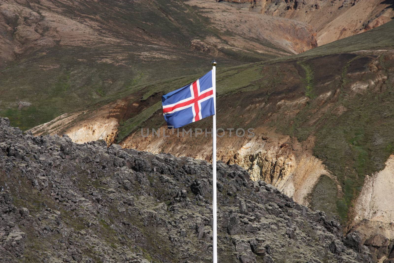 Icelandic flag. Beautiful mountains in Iceland. Famous volcanic area with rhyolite rocks - Landmannalaugar. Lava field black rocks.