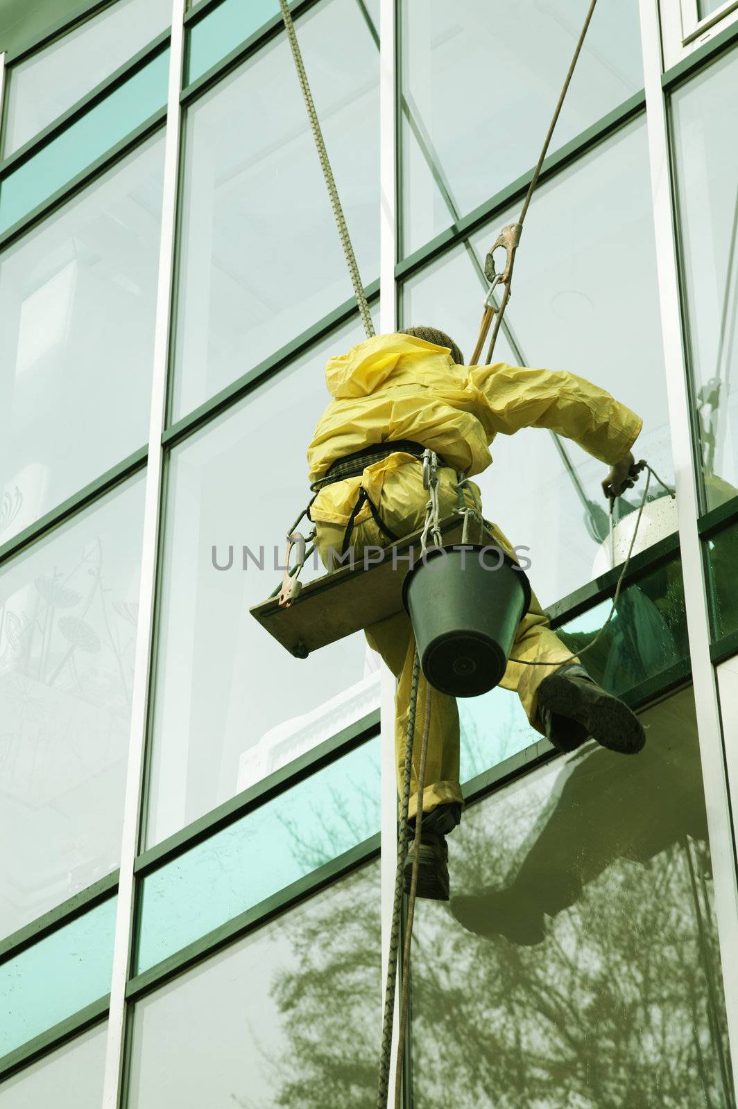 Window cleaner man climbing a skyscraper facade 