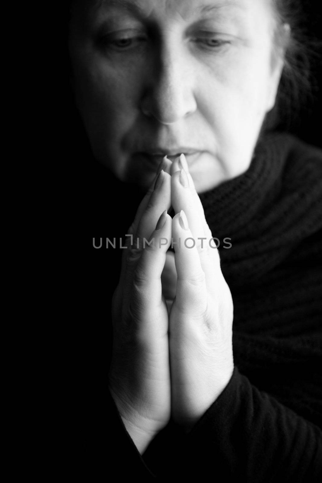 woman praying or deep in thoughts, special black and white film-looking photo f/x,focus on hands (nearest fingers)