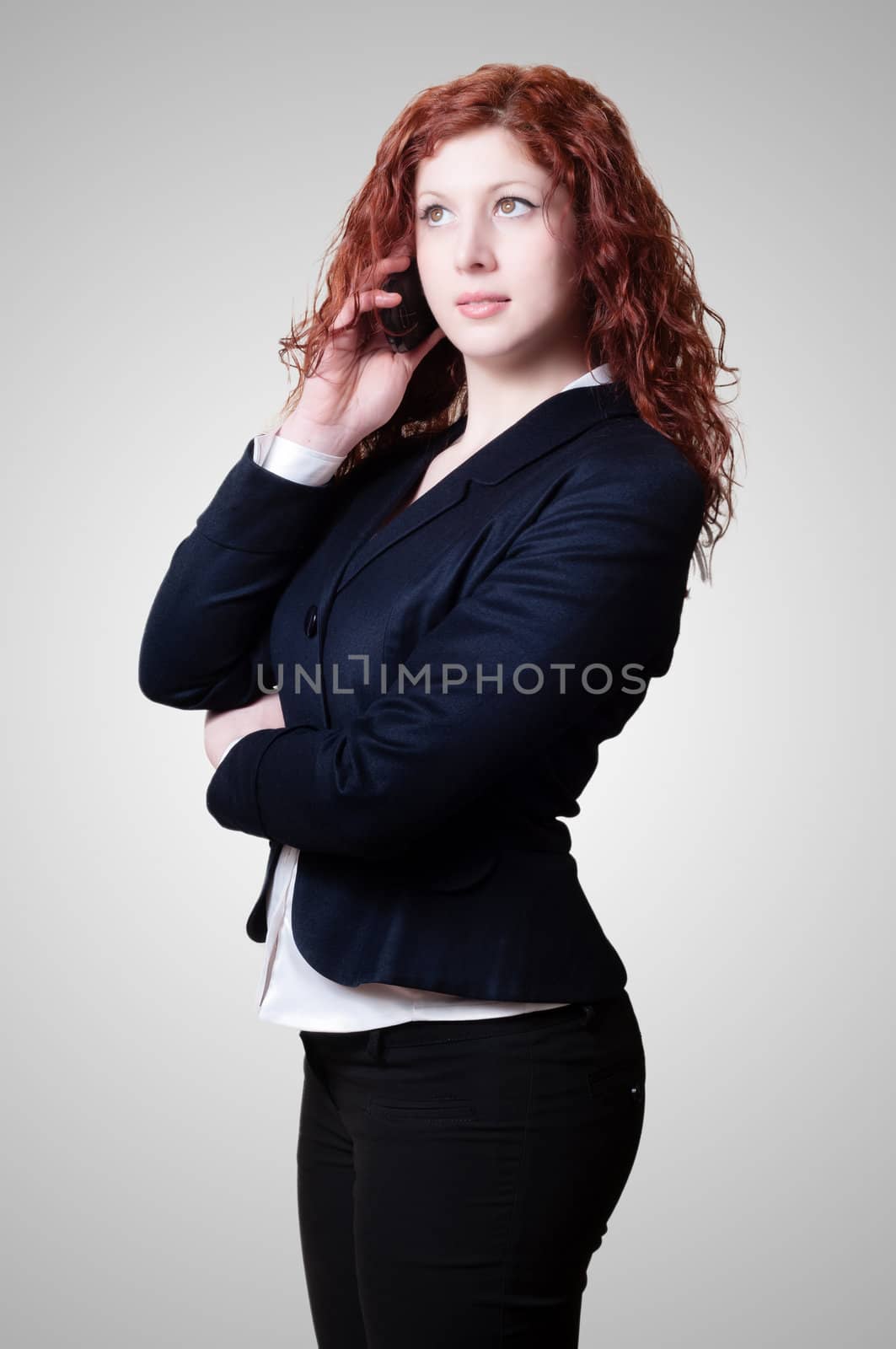 long red hair businesswoman on the phone on gray background