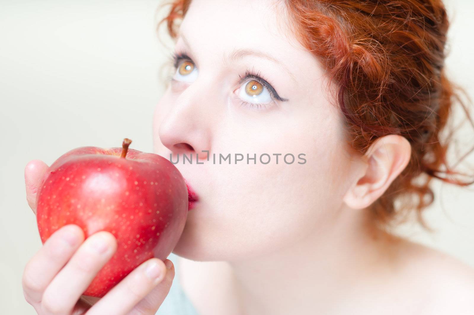 beautiful red hair and lips girl kissing apple on white background