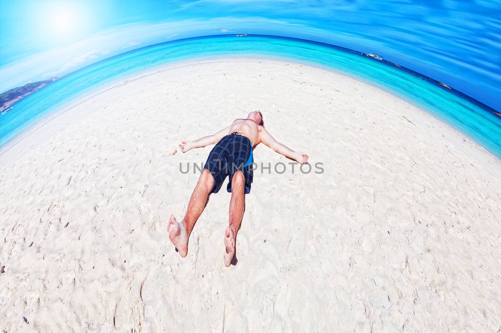 man lies on a  beach on an ocean coast by elena_shchipkova