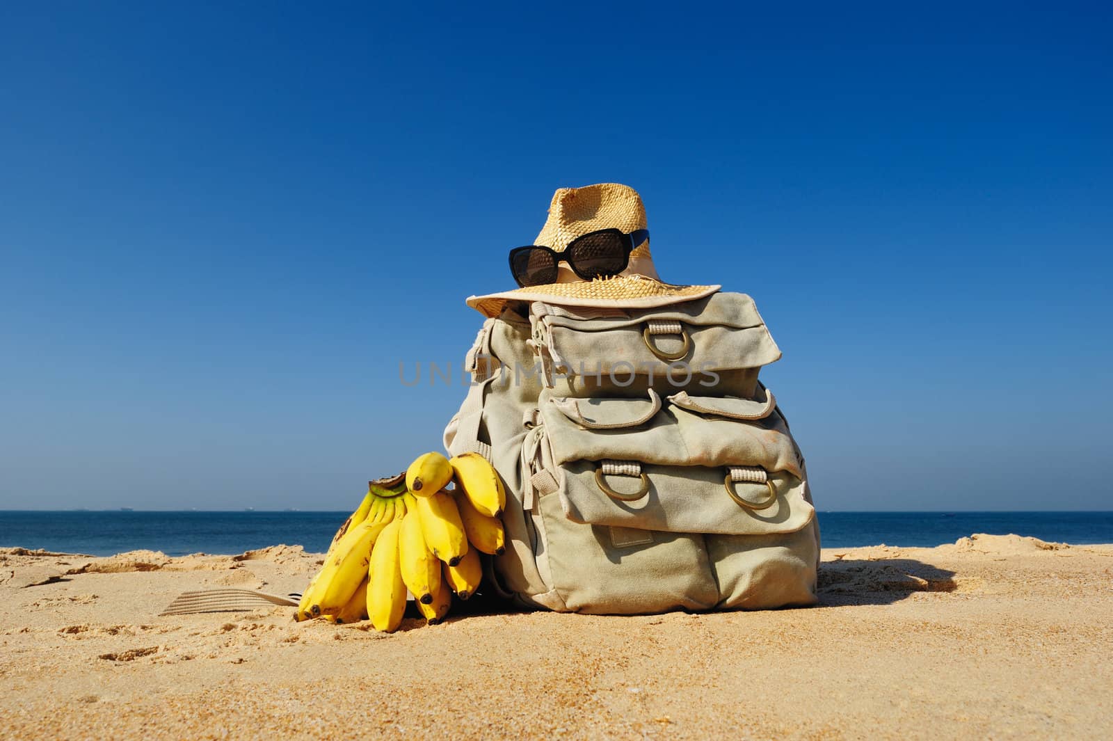 Rucksack, hat and bananas on the sandy beach