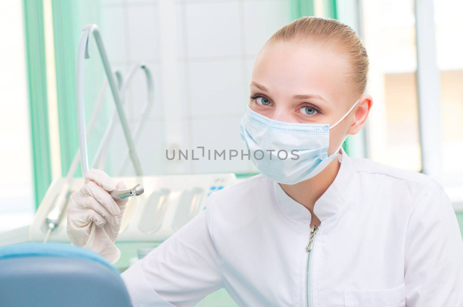 female dentists in protective mask holds a dental drill, the doctors at work