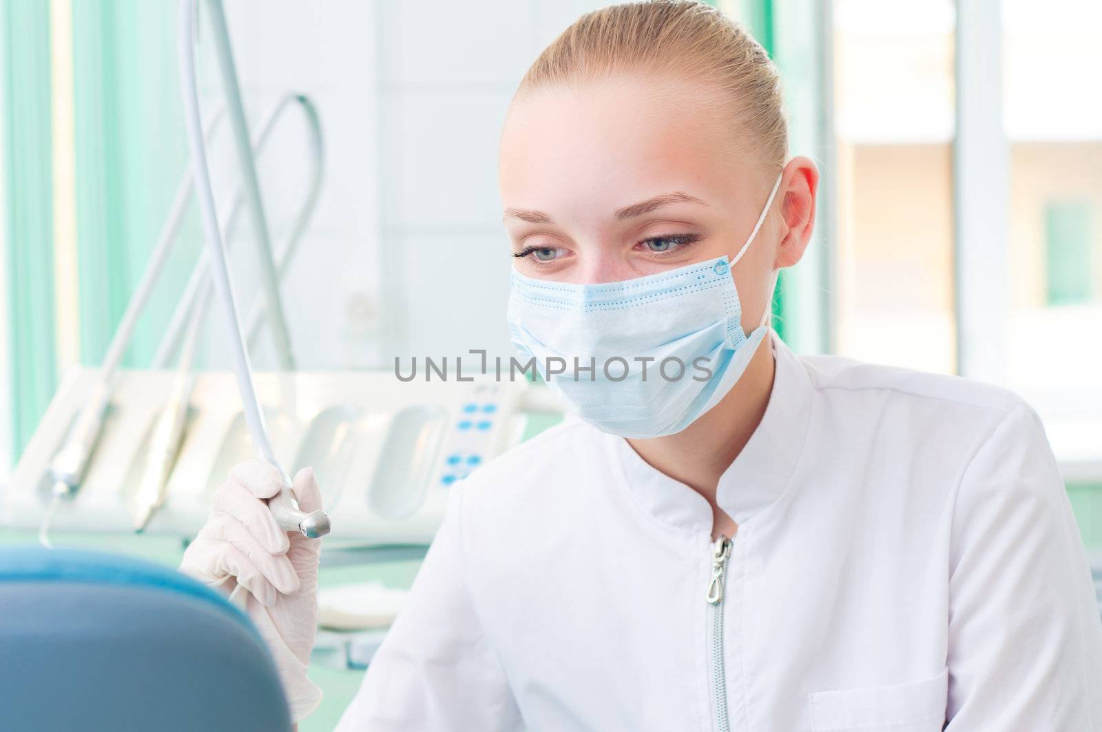 female dentists in protective mask holds a dental drill, the doctors at work