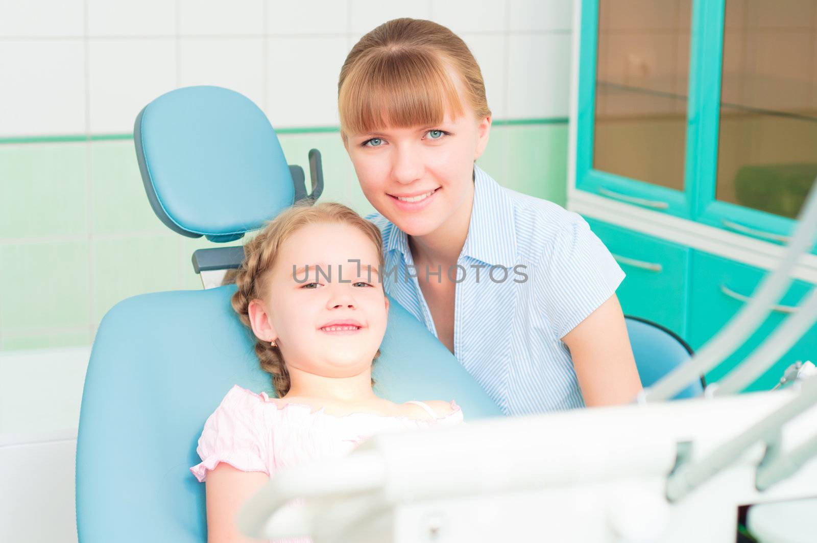 mother and daughter visit the dentist, the child is sitting in the dental chair and mother near