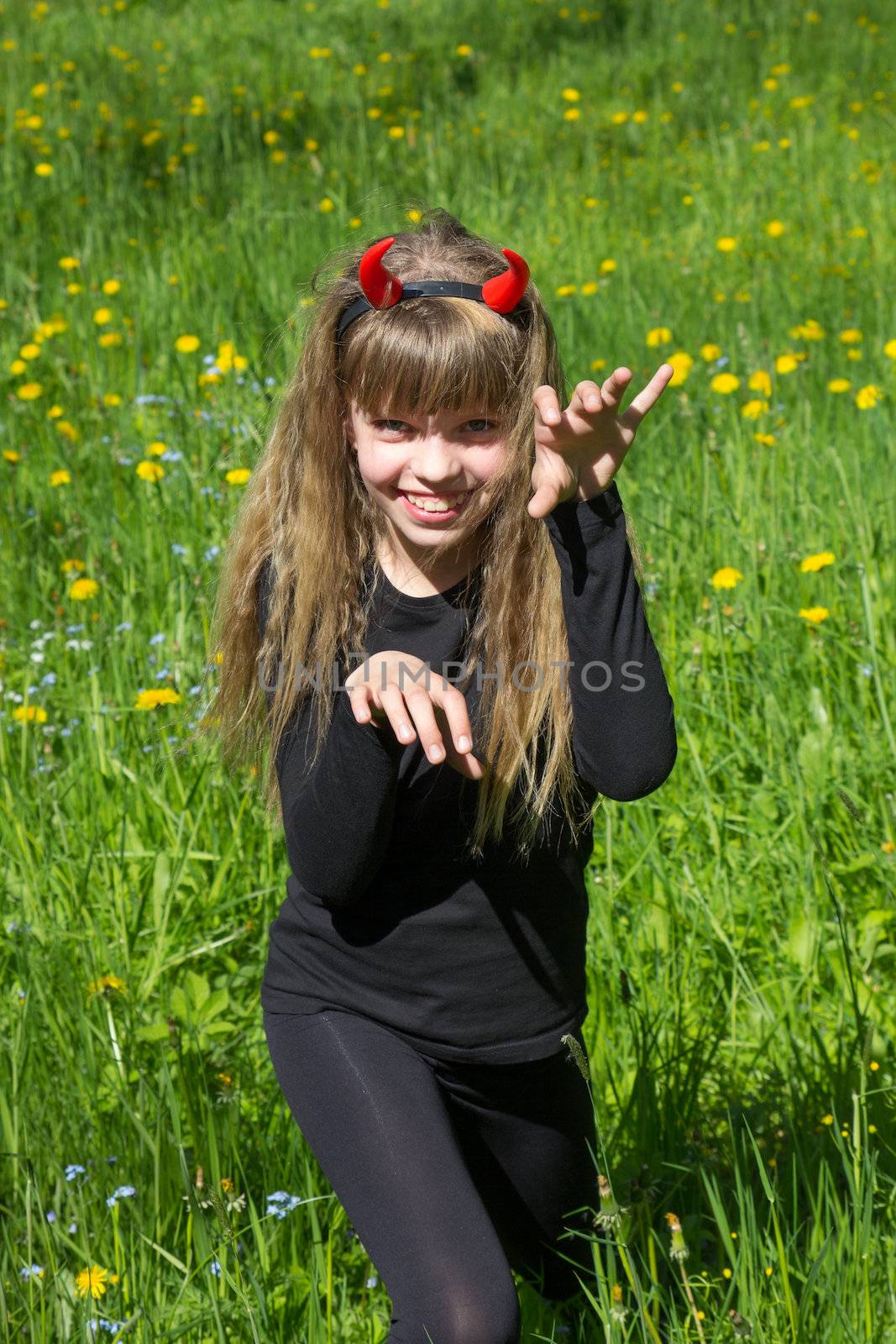 little devil girl in a green dandelion field