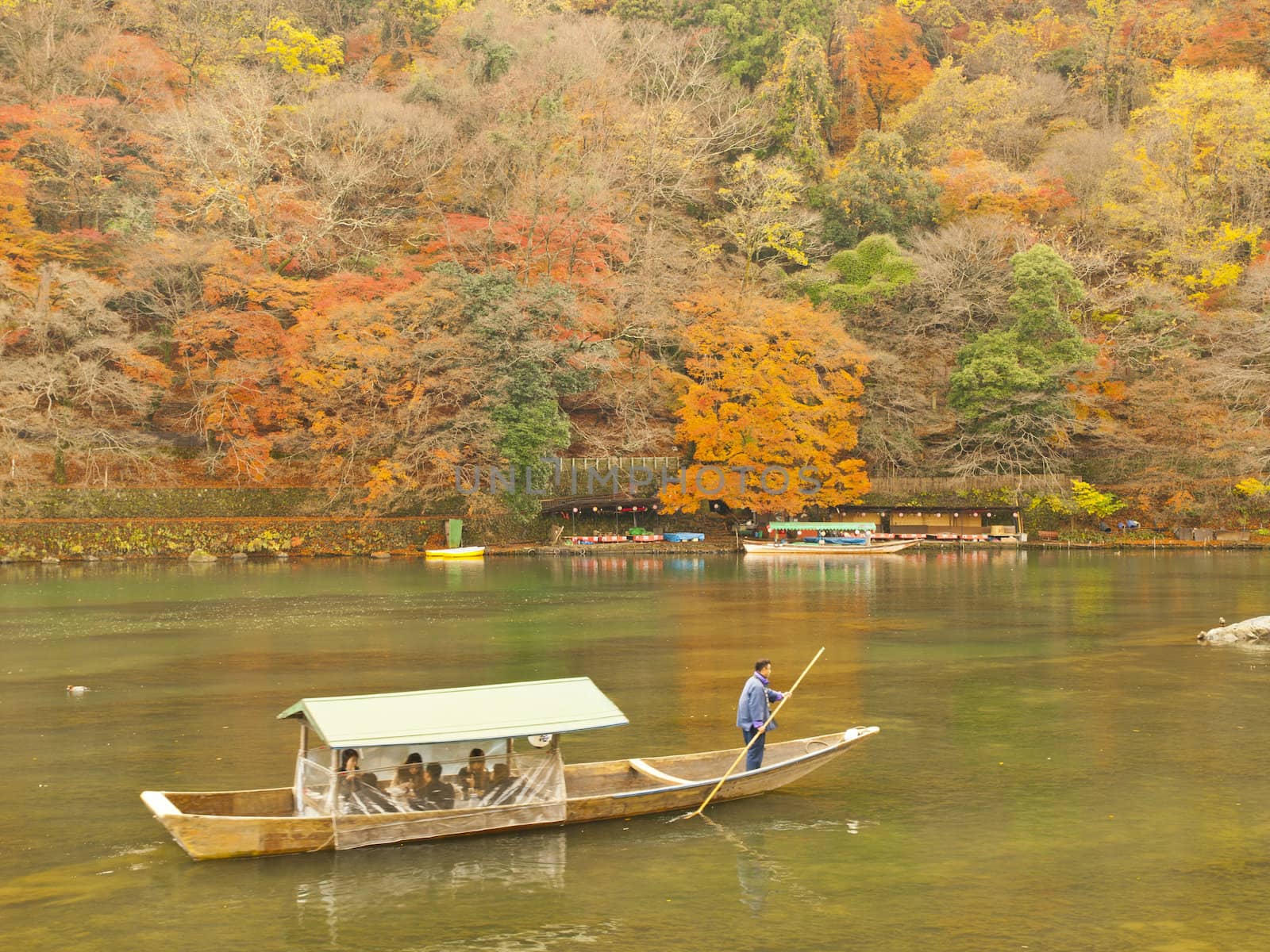 ARASHIYAMA, KYOTO, JAPAN - CIRCA DECEMBER 4, 2009: Boat with tourists on Katsura river in Arashiyama area, Kyoto, Japan on December 4, 2009.