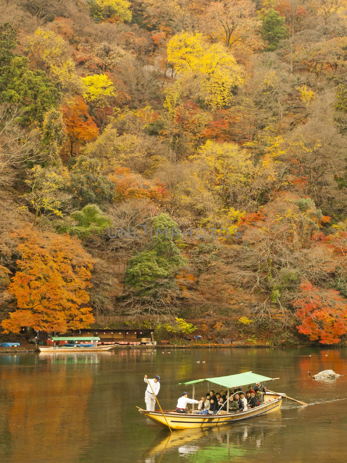 ARASHIYAMA, KYOTO, JAPAN - CIRCA DECEMBER 4, 2009: Boat with tourists on Katsura river in Arashiyama area, Kyoto, Japan on December 4, 2009.