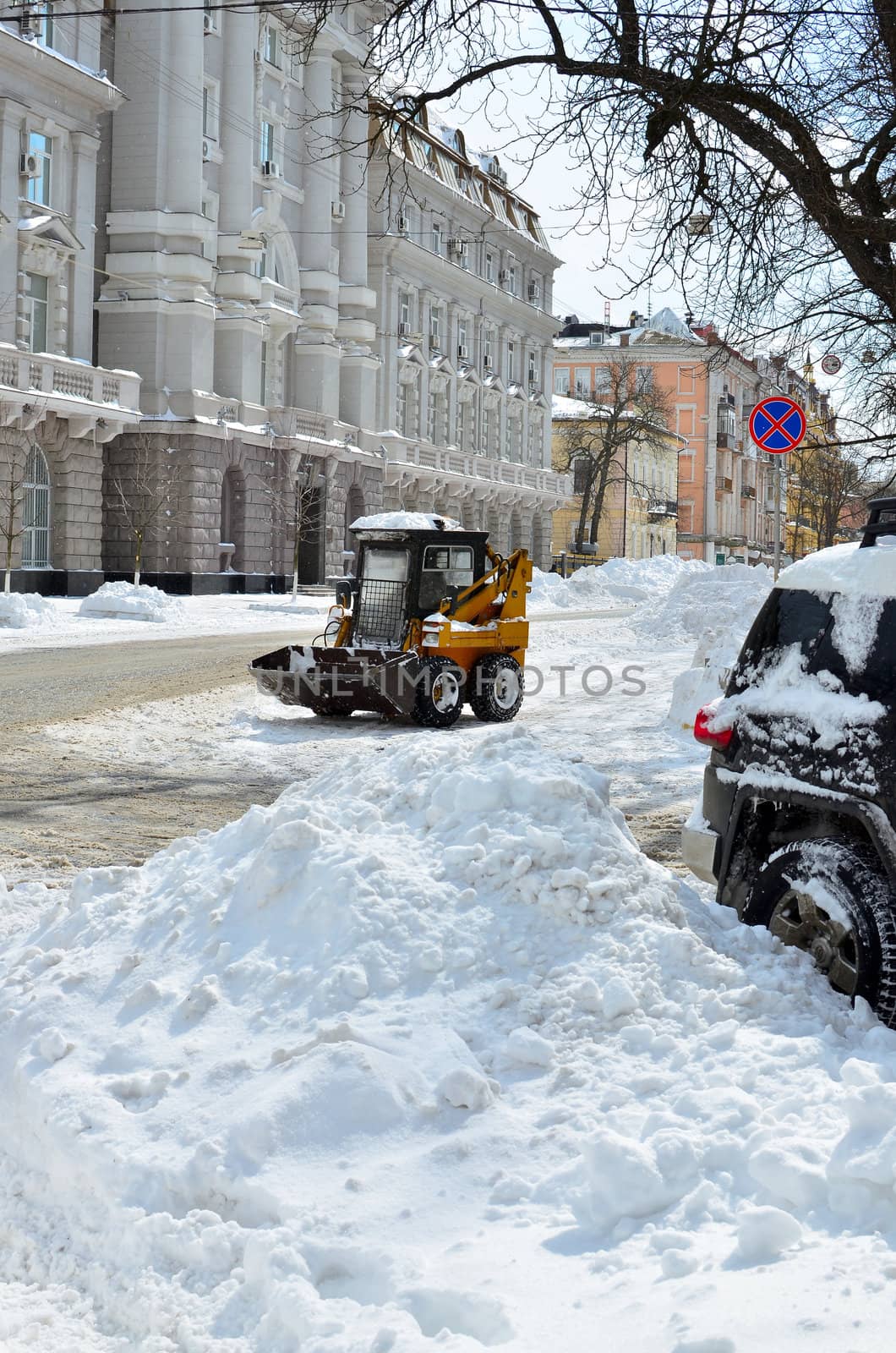 yellow tractor cleaning the snow on a street