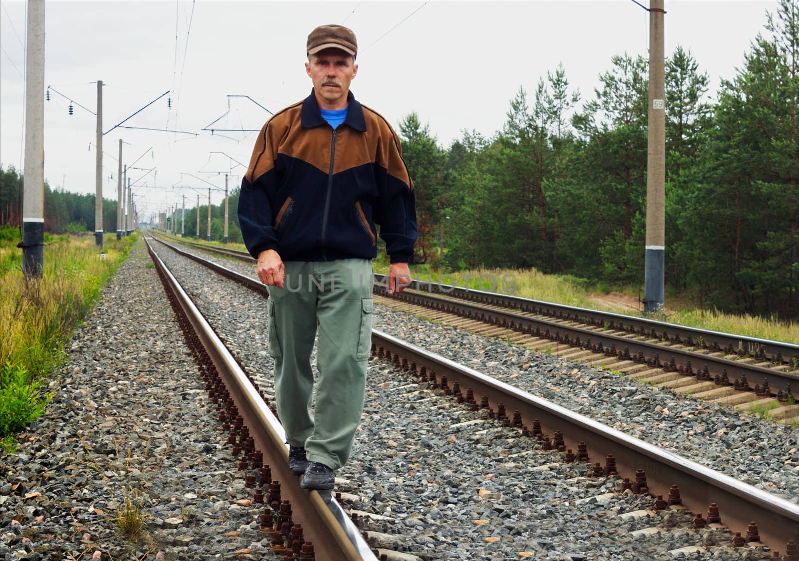 An elderly man walking on railway track
