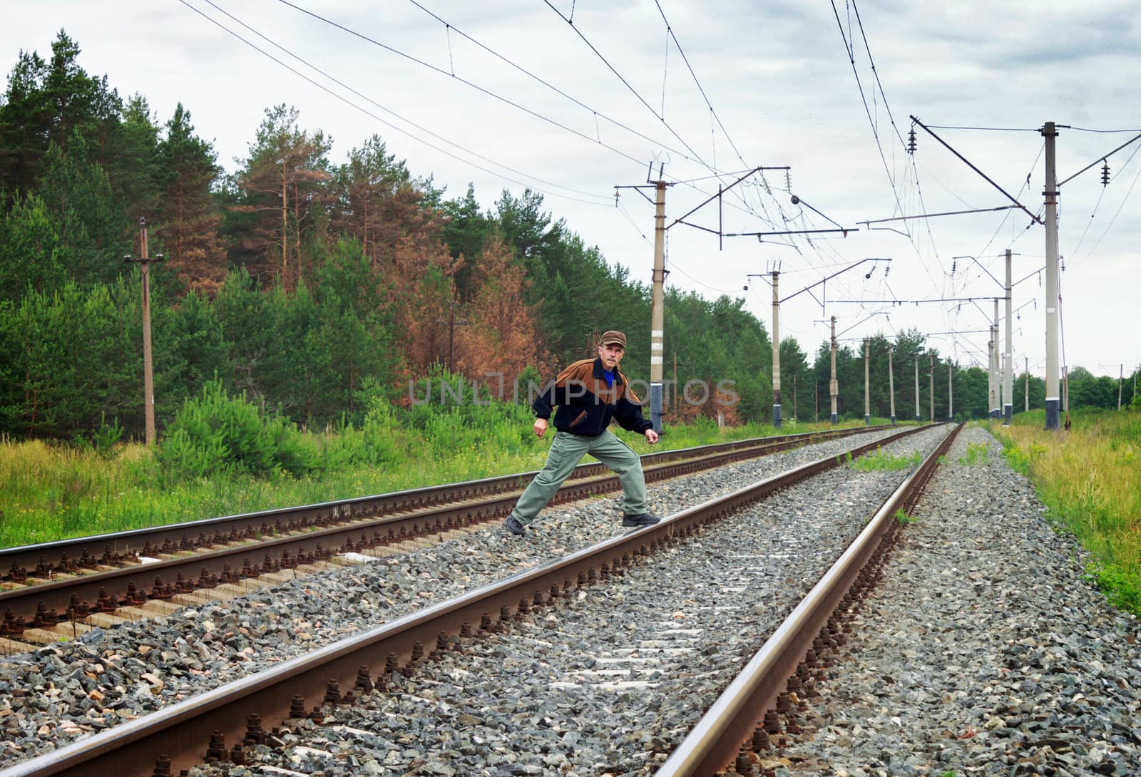 An elderly man risky crosses a railway embankment