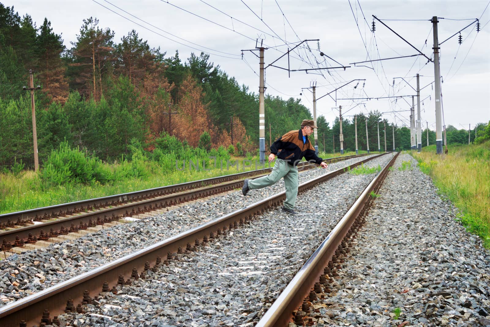 Elderly man risky crosses a railway embankment