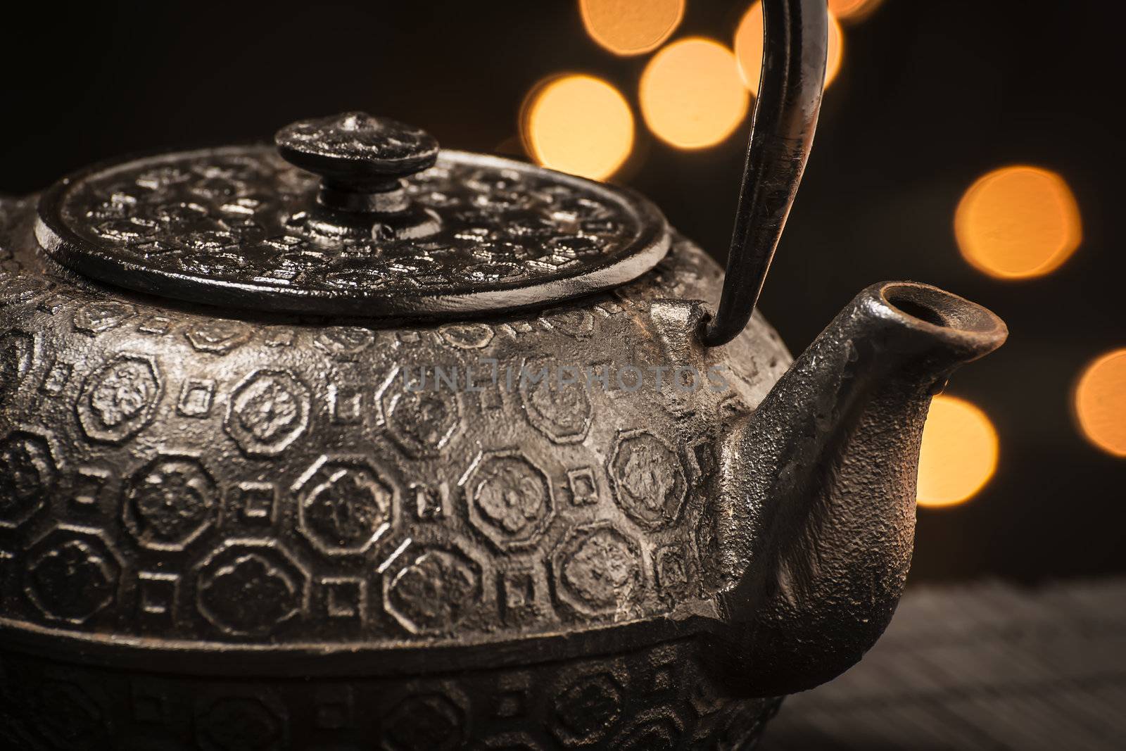 Closeup of a black, cast-iron teapot on a black bamboo mat
