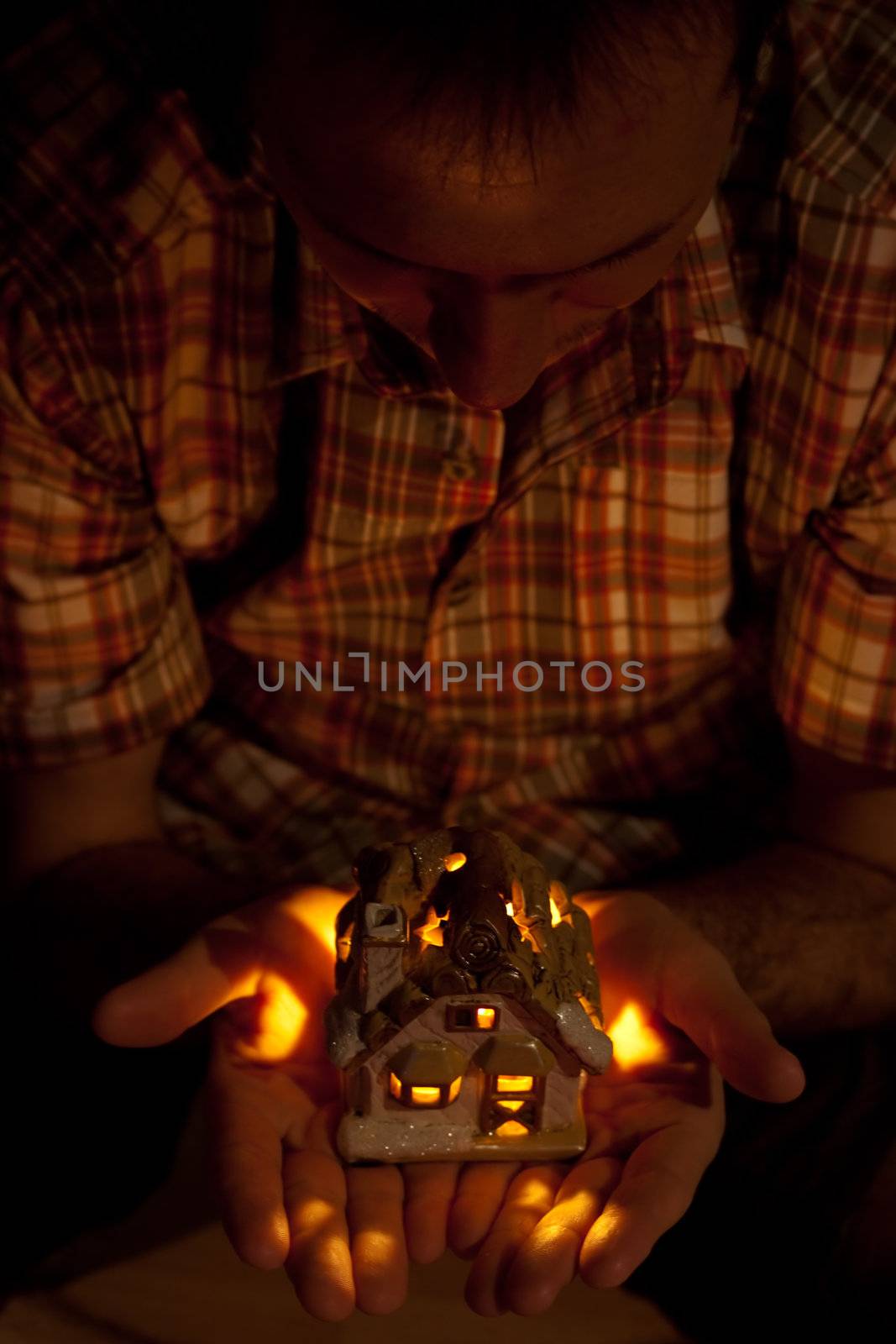 decorative house with a candle in the hands of man