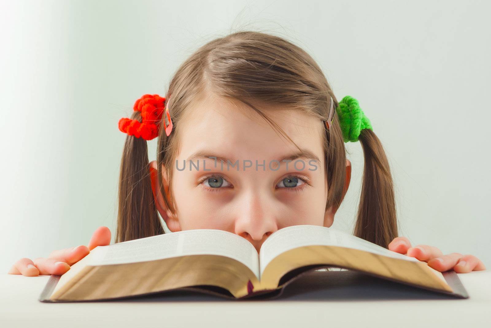 Surprised teen girl looking from behind the Bible