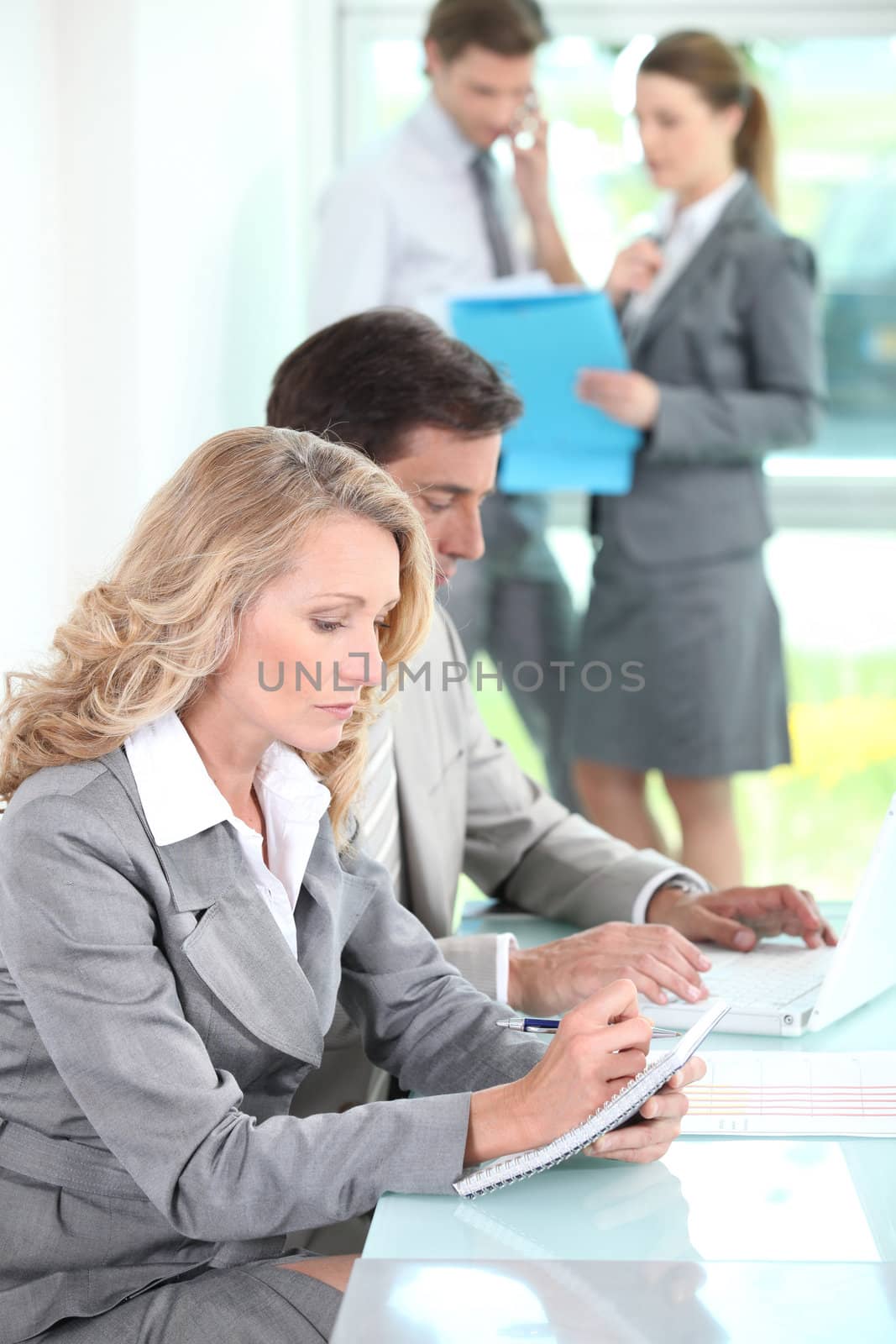 Woman writing in a notepad in an office environment
