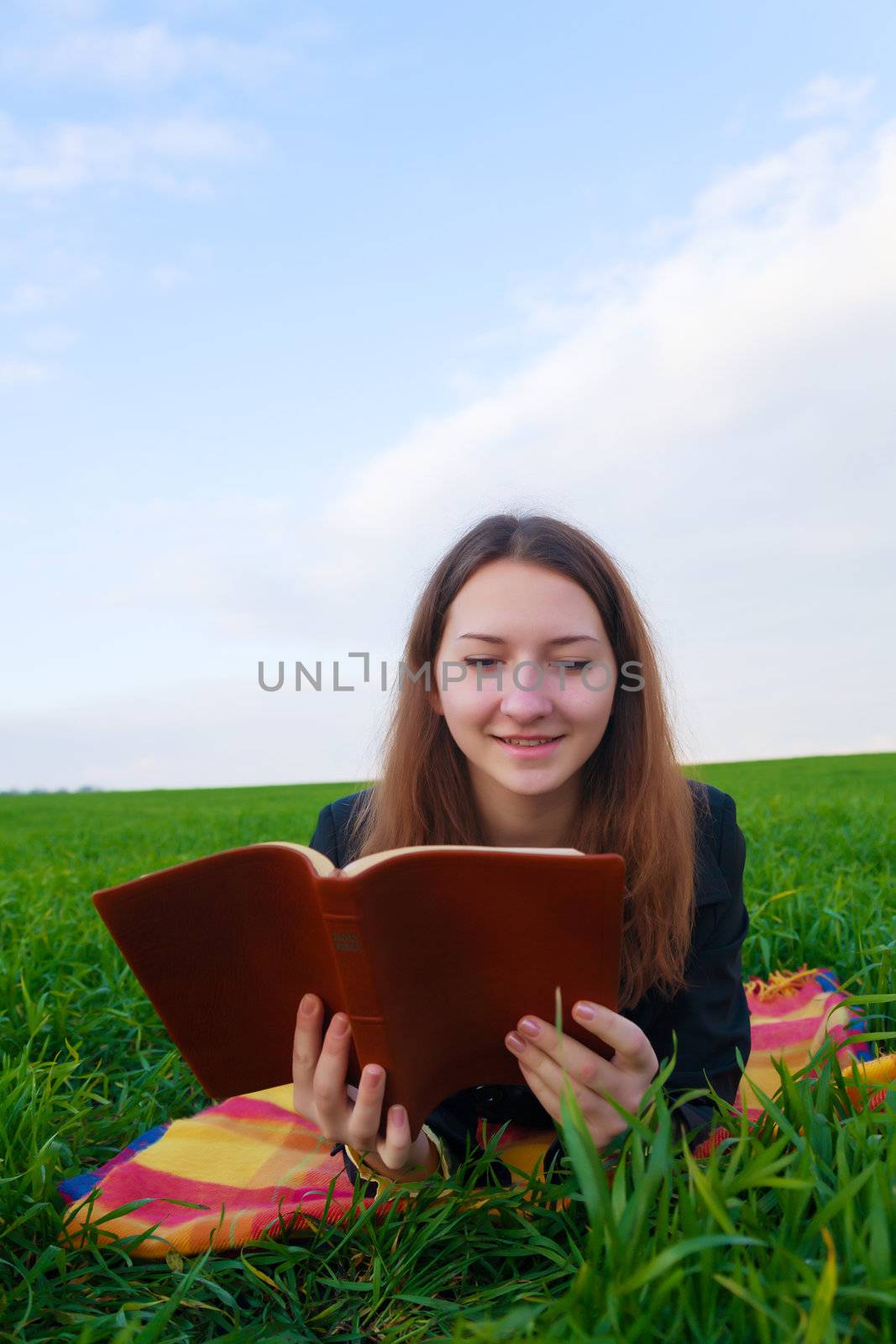 Teen girl reading the Bible outdoors at sunset time