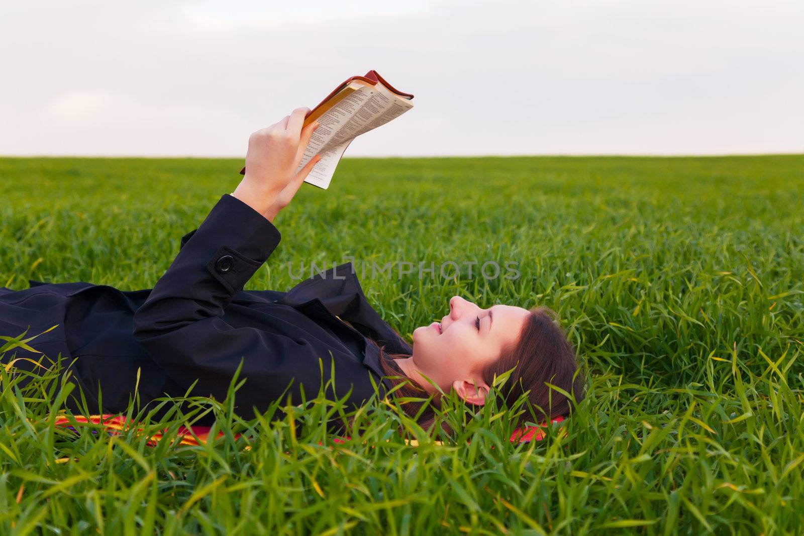 Teen girl reading the Bible outdoors by AndreyKr