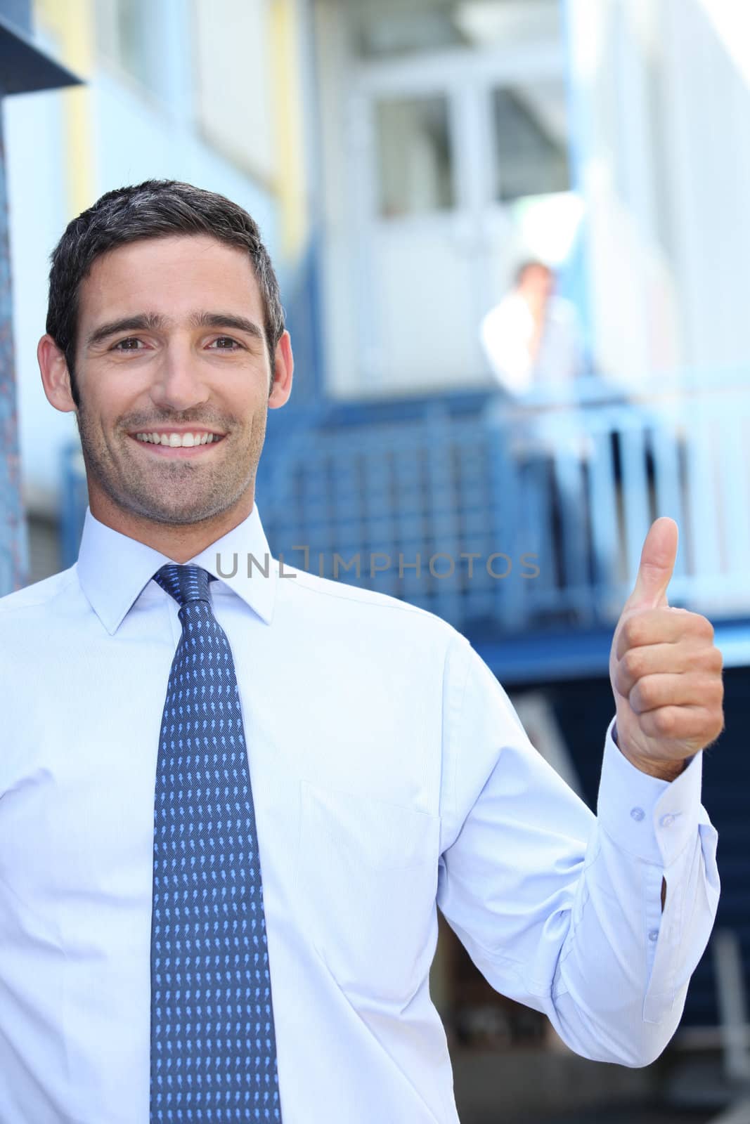 Man giving the thumbs up outside the workplace by phovoir