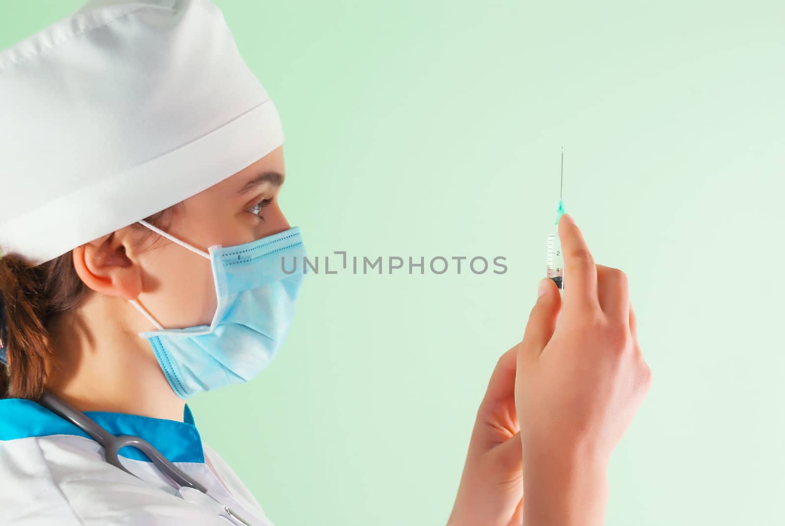 Young lady doctor with syringe against light background