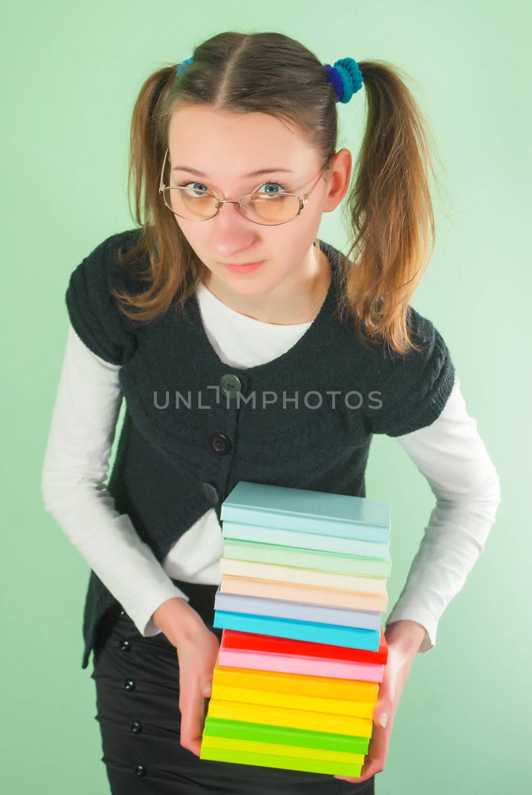 Teen girl with a stack of books against light green background