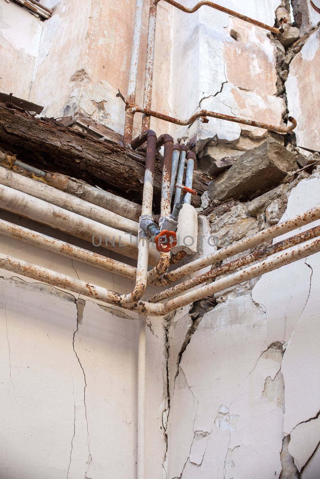 View of demolished house with tap, tubes and cracked wall