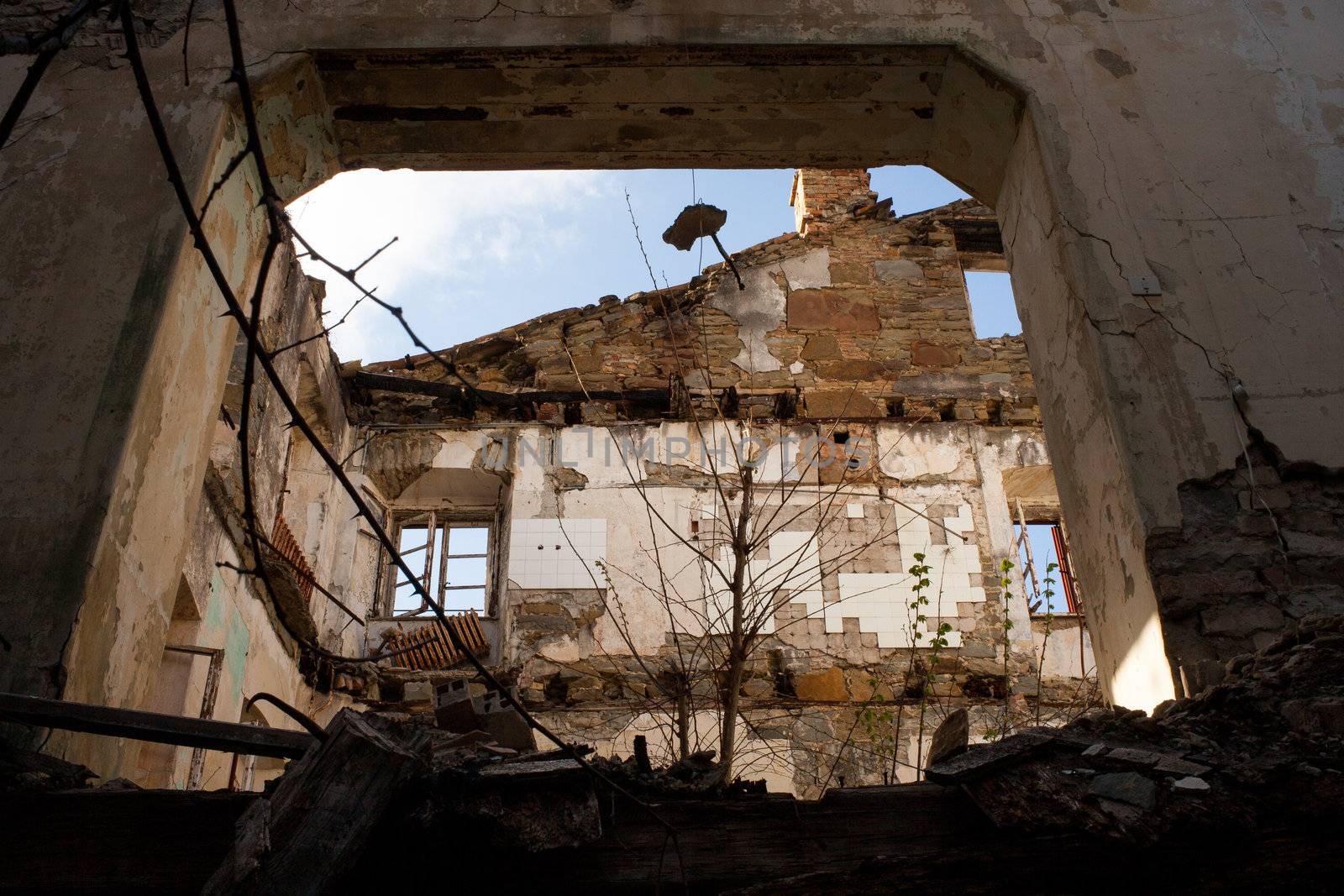 View of demolished house with rubble and cracked wall