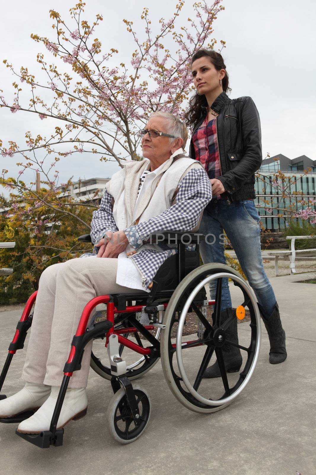 Young woman pushing an elderly lady in a wheelchair