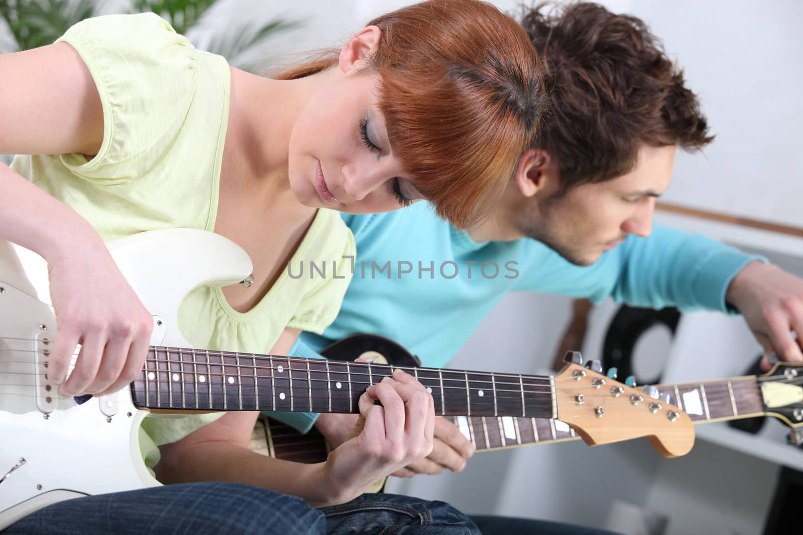 Young couple tuning and playing guitar by phovoir