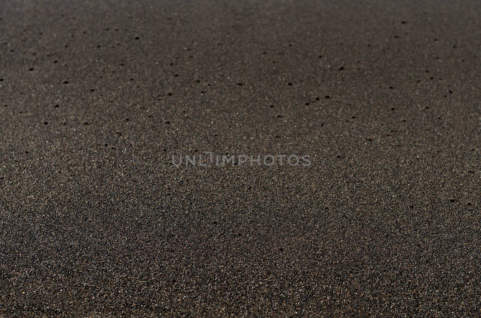 Black sand volcanic beach background in Bali, Indonesia. Shallow depth of field.