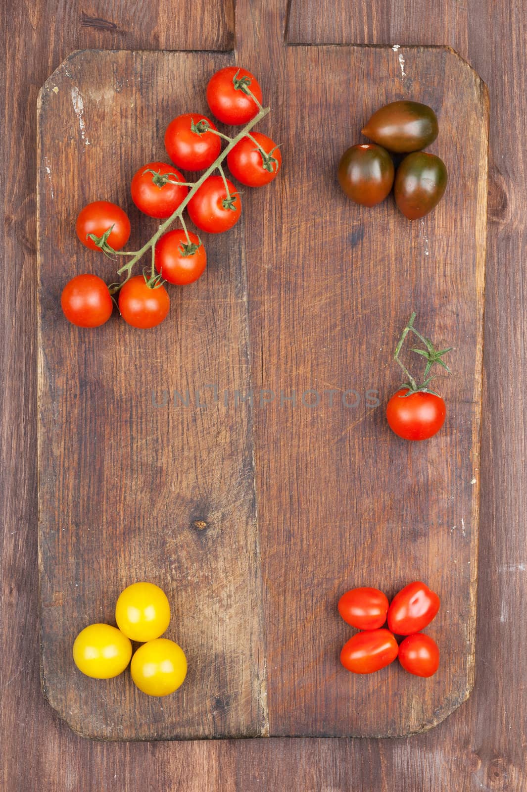 Set of different varieties of cherry tomatoes on a dark wooden background