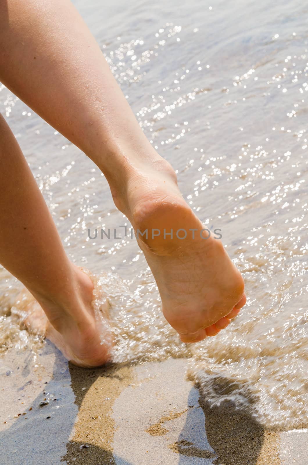 young woman take a walk on wet seashore. Body part.