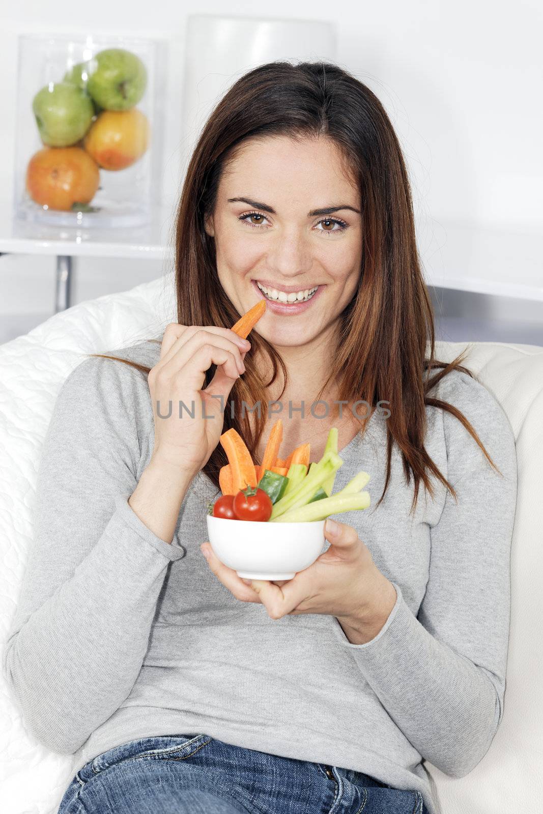 smiling woman on sofa with vegetable salad