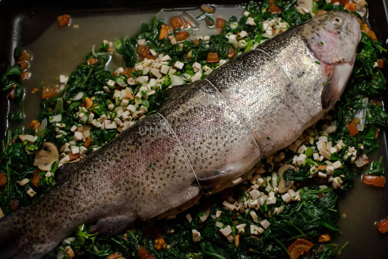 filled rainbow trout (salmon trout) on spinach with tomatoes and mushrooms ready for the oven