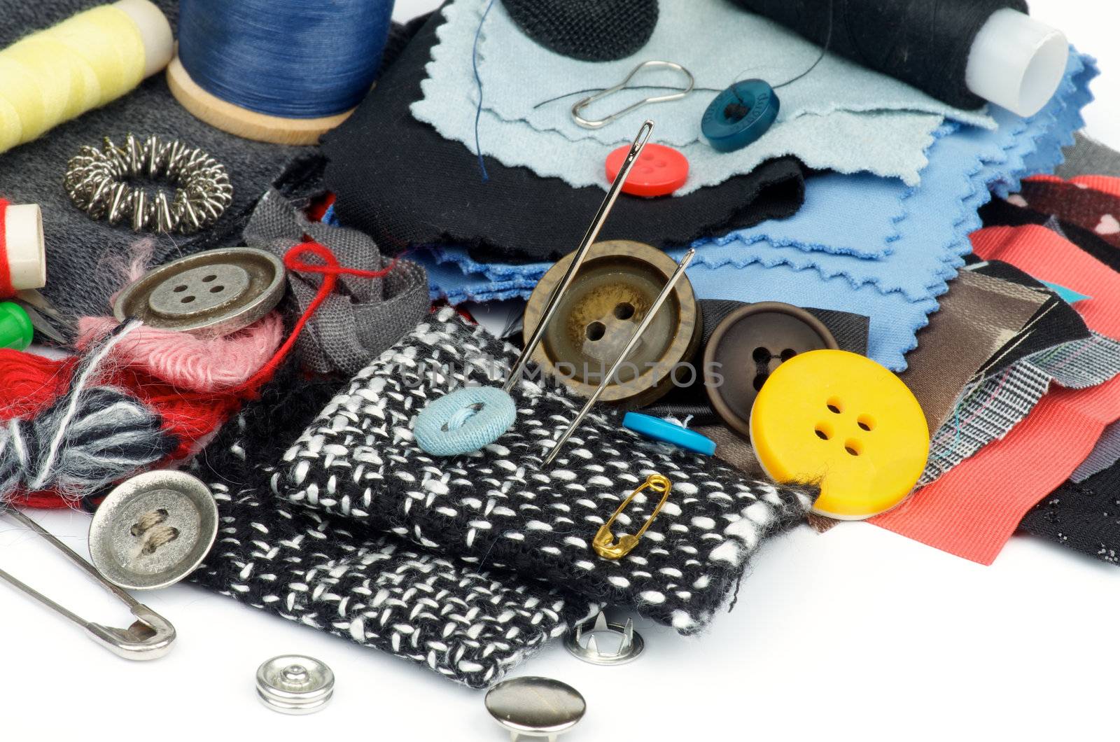 Sewing Items with Various Buttons, Pins, Spools, Threads and Textile closeup on white background