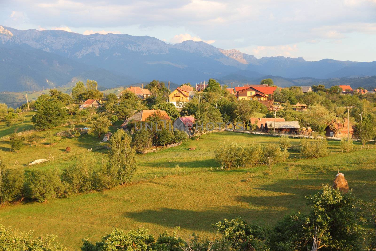 Piatra Craiului National Park in Romania - mountain landscape with small village in sunset light.