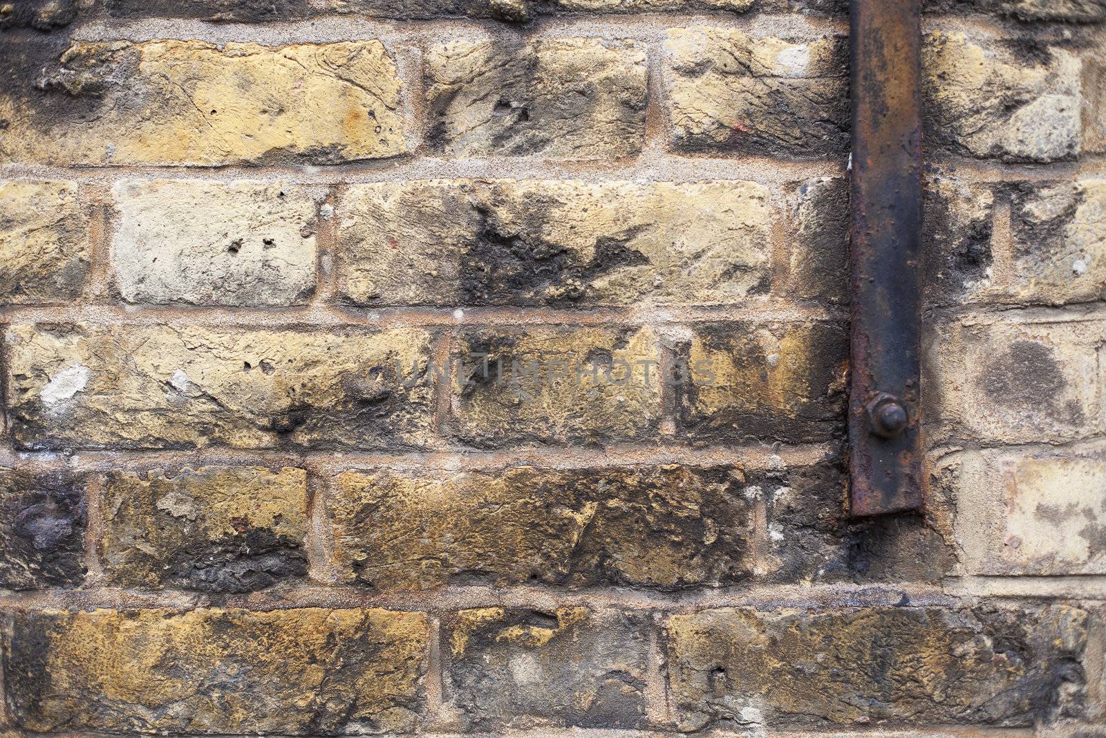 Brick background with chips and discoloration and a metal bar