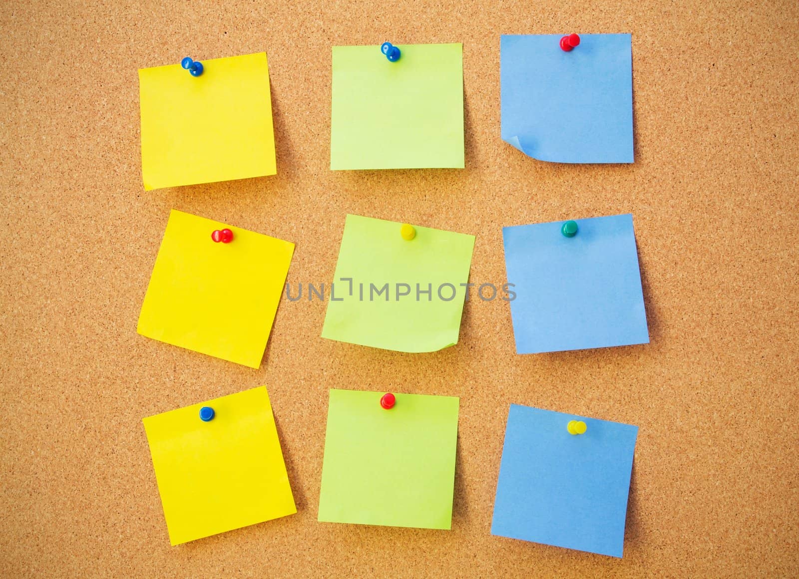 Colour note papers on pin board. Cork background 