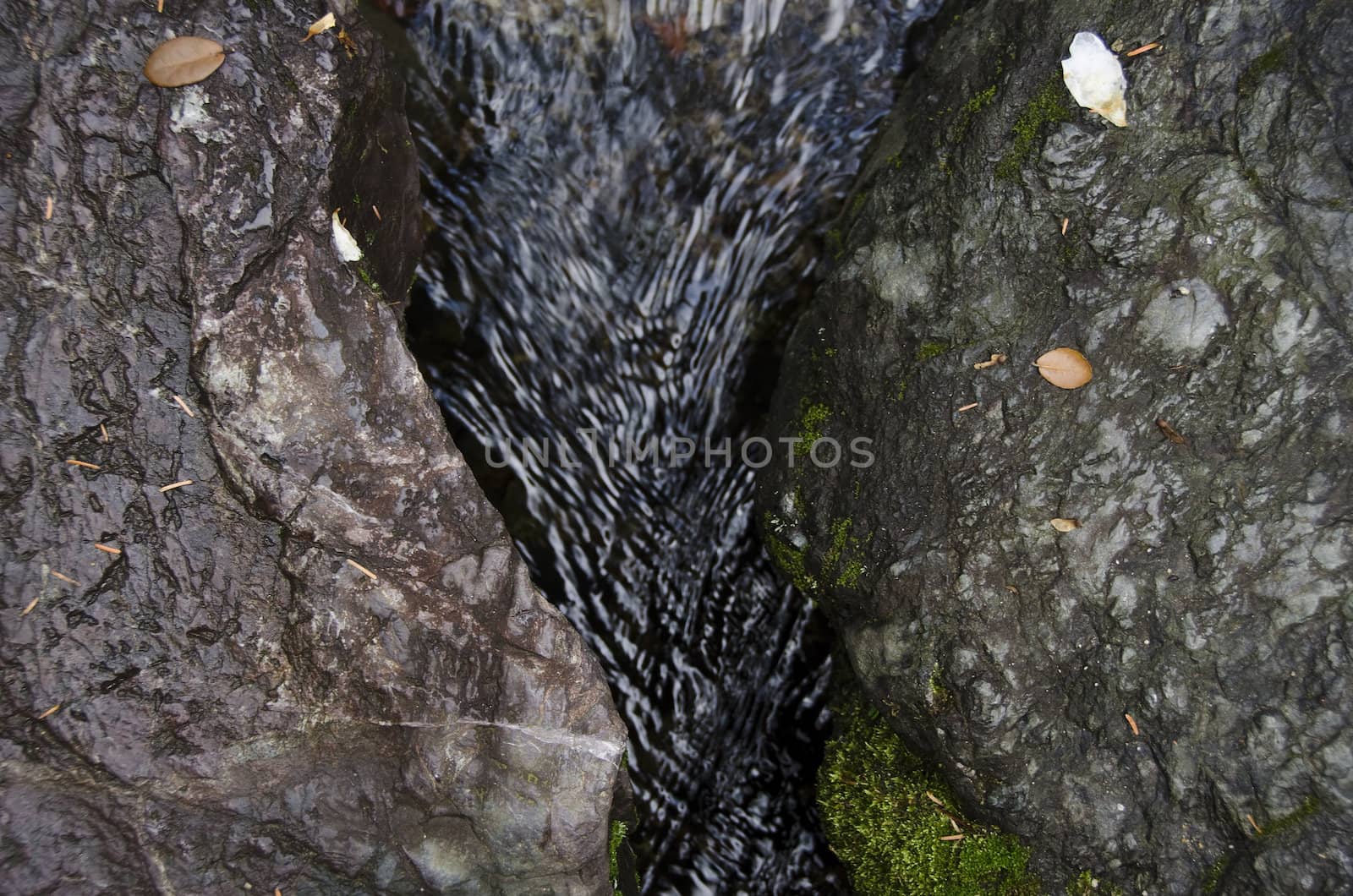 Small water stream in between two rocks in autumn