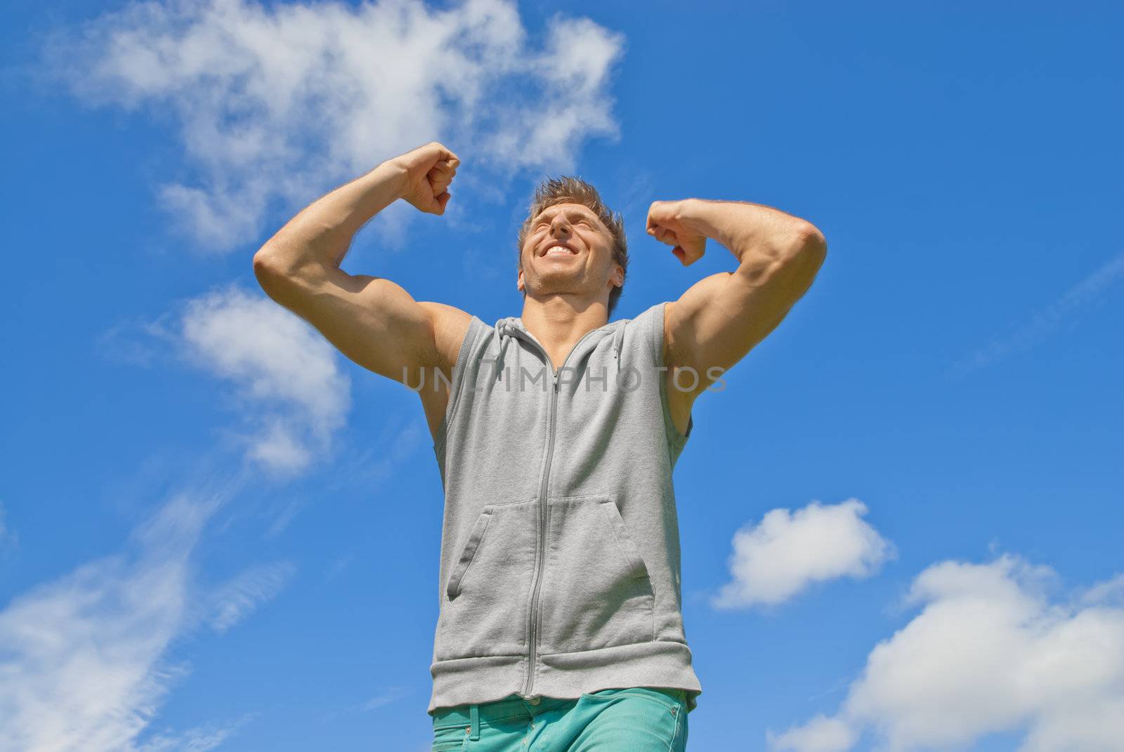 Energetic and happy young man on blue sky background.